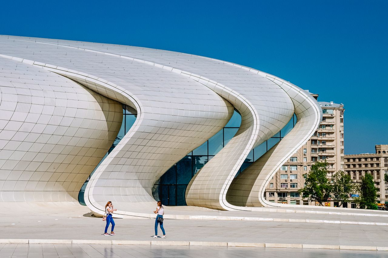 Services Modern architecture of Heydar Aliyev Center in Baku, Azerbaijan with people outside.