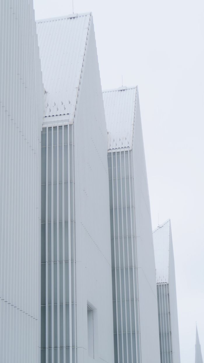 Services Minimalist geometric architecture showcasing white angular structures under a soft sky.
