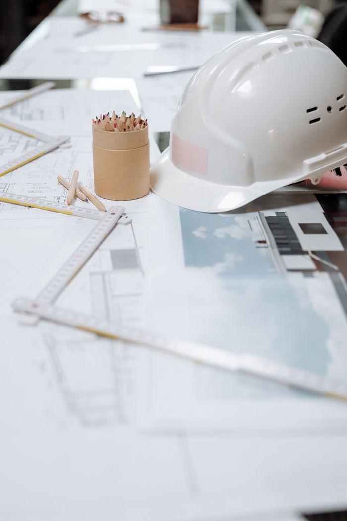 Services A detailed view of an architect's desk with plans, a hard hat, and drafting tools.